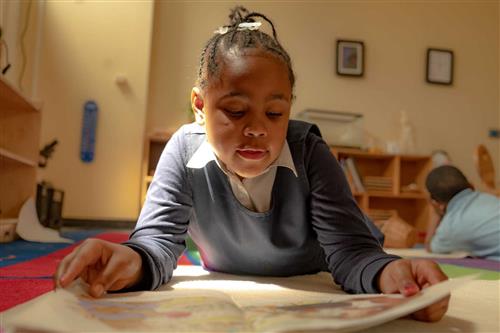 Young girl lying on floor reading a book 